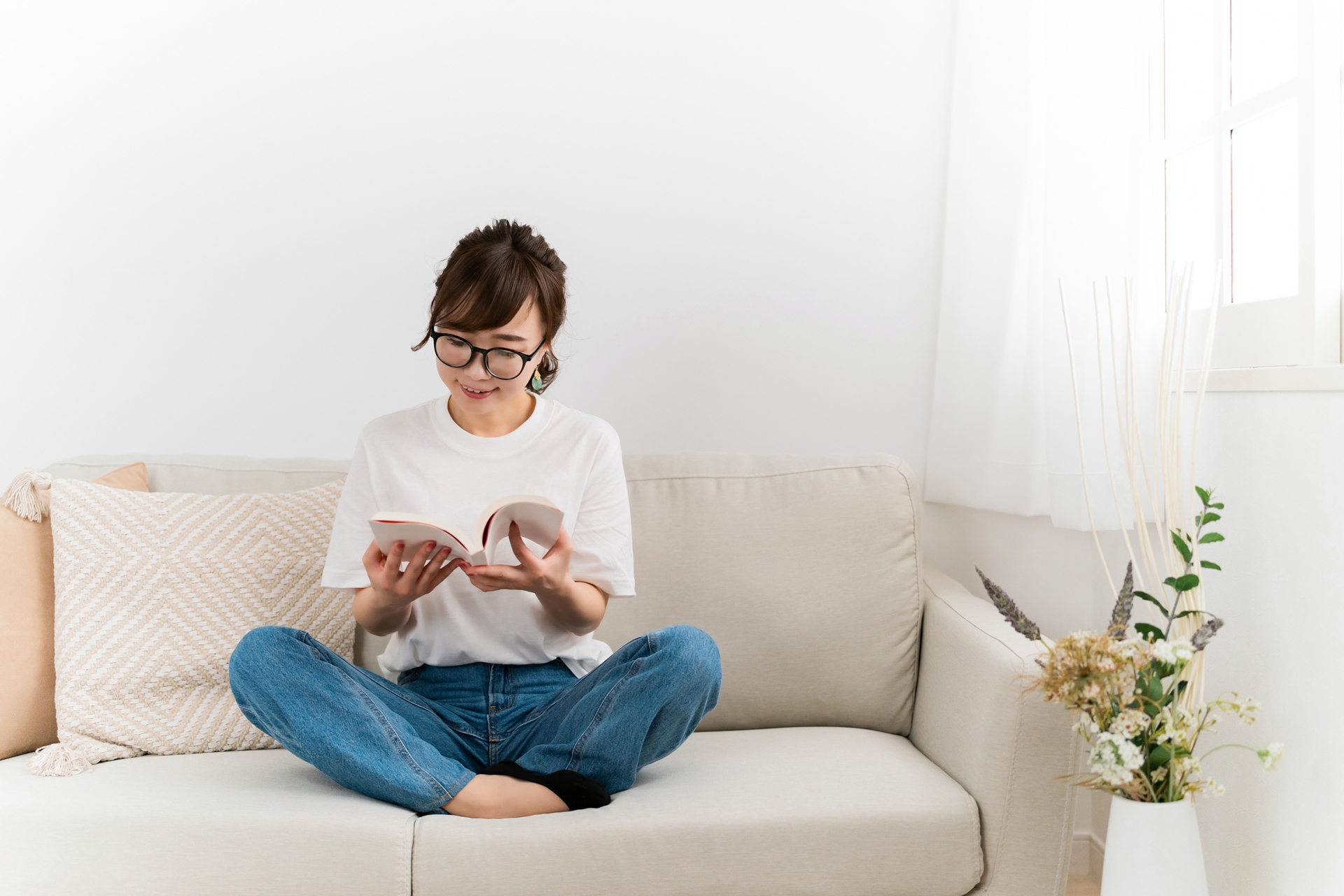 ソファでくつろぎながら読書する女性