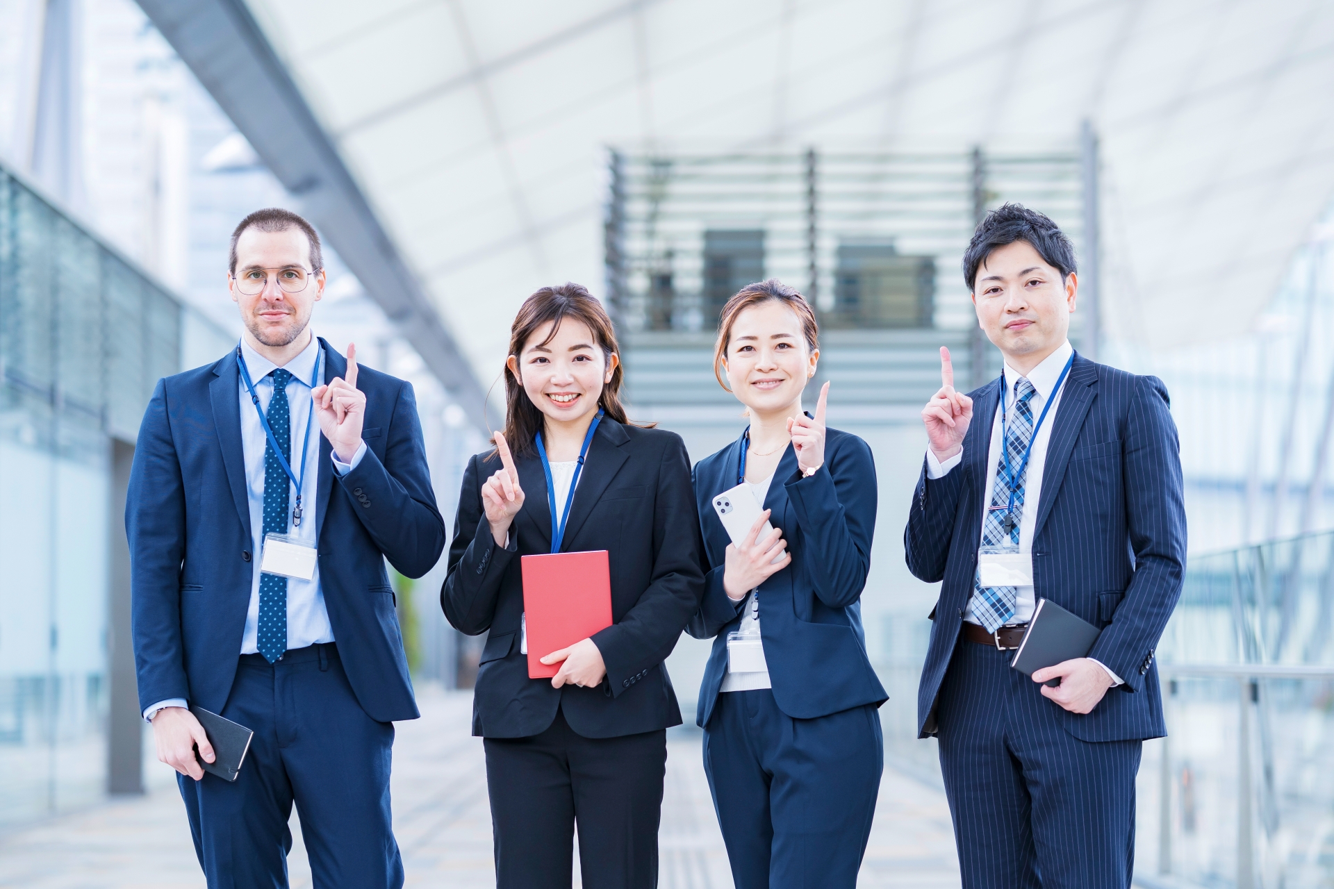 笑顔で指を立てる4人のビジネスパーソン