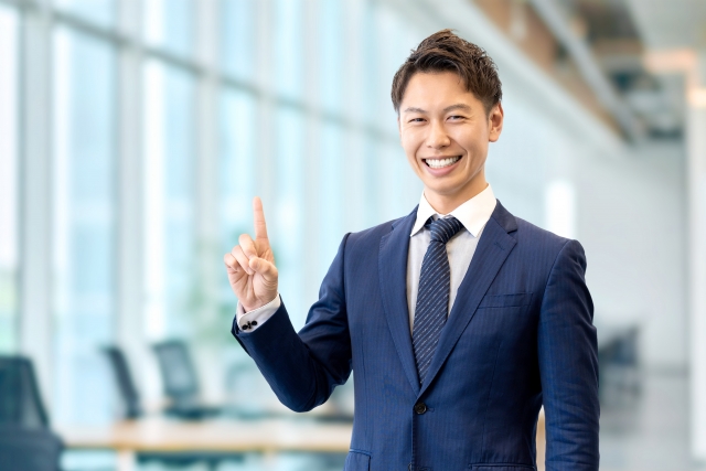 人差し指を立てて案内する男性ビジネスマン