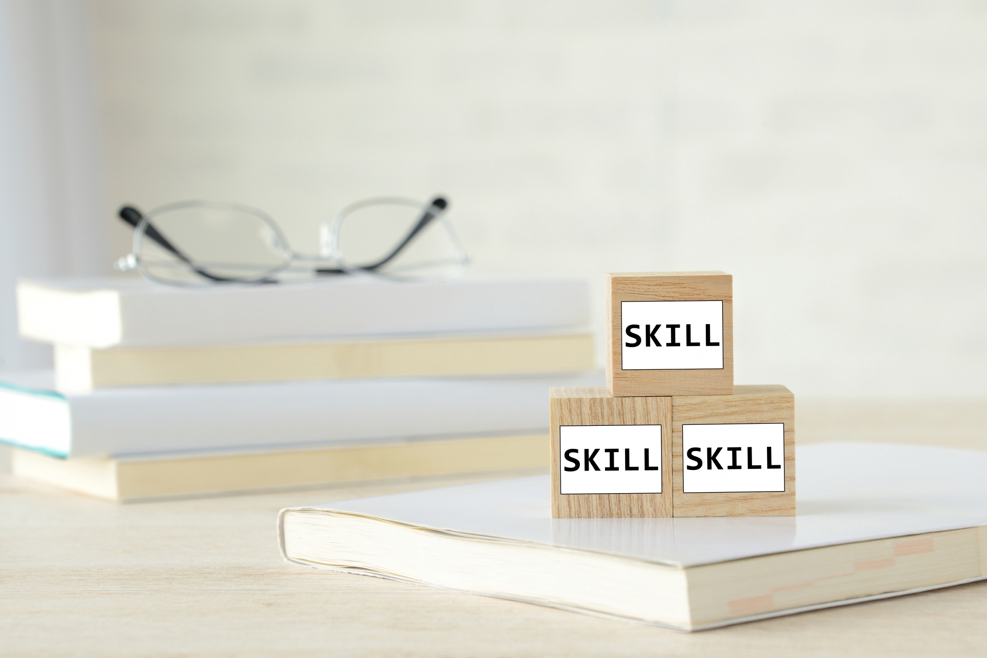 積み上げられた本とメガネ、「SKILL」のブロック